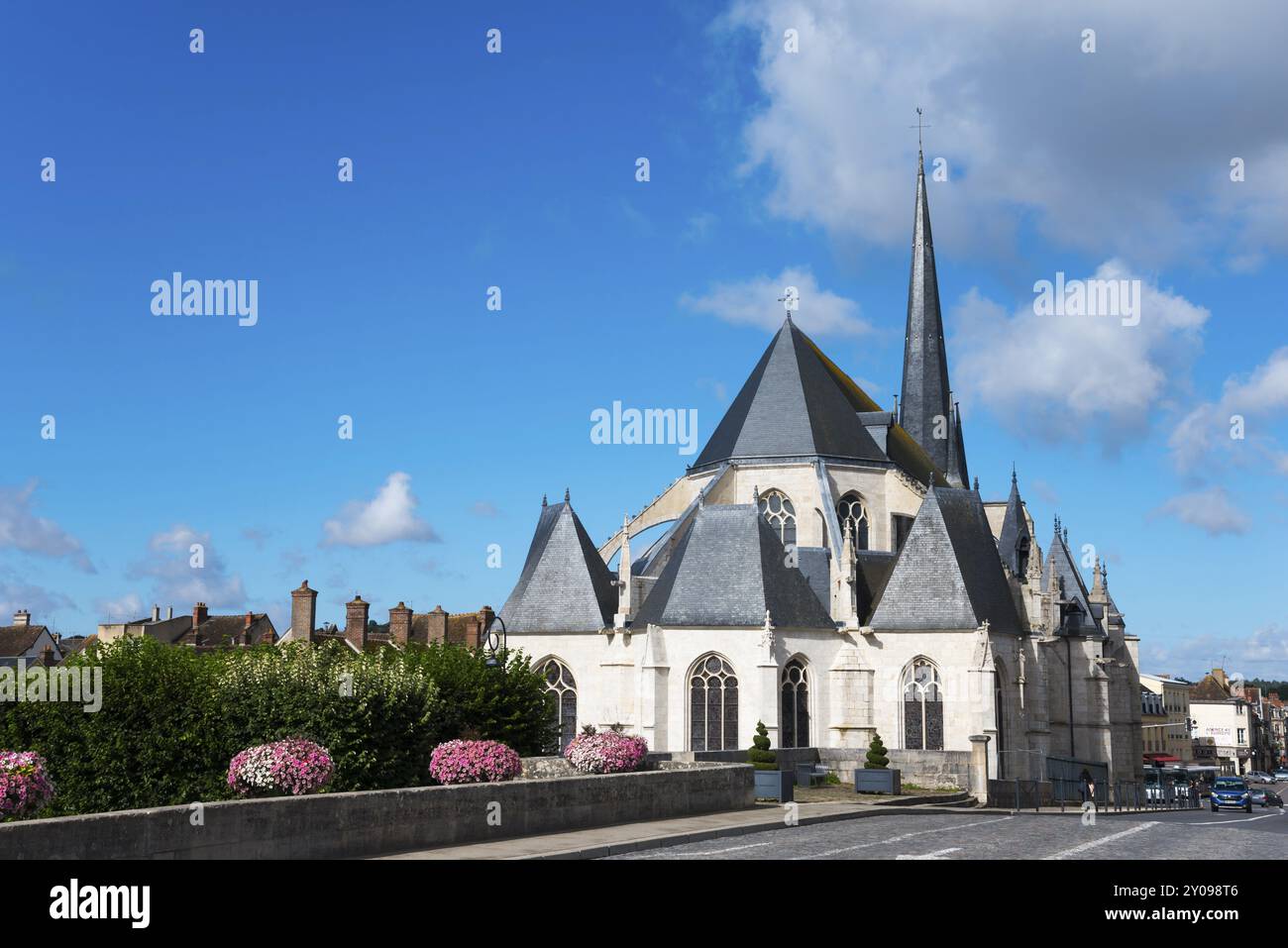 Gotische Kathedrale mit hohen Tuermen und einem klaren Himmel mit Blumen im Vordergrund, Kirche, Eglise Saint-Jean-Baptiste, Nemours, Fluss Loing, DEP Banque D'Images