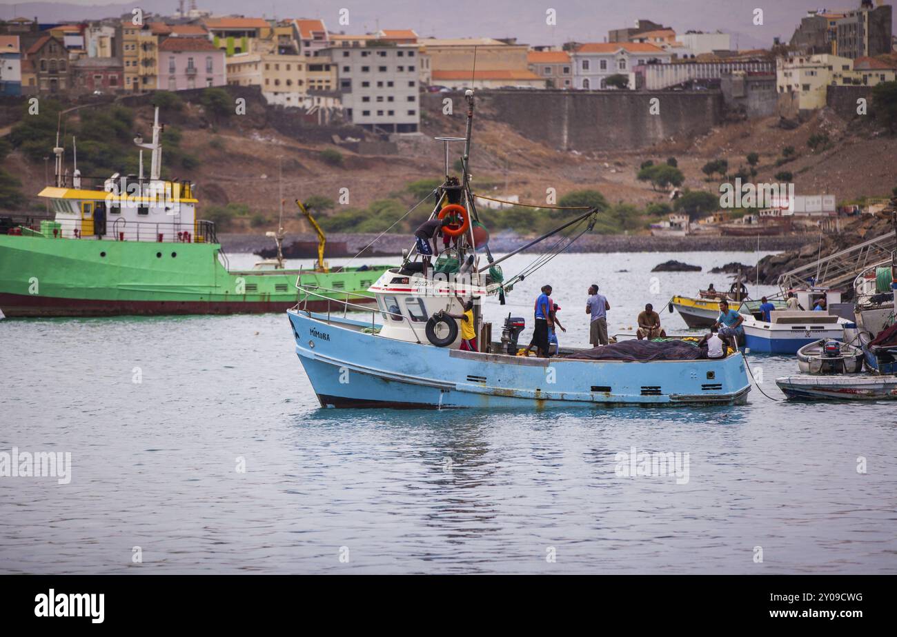 Pêcheurs mettant les voiles sur un bateau bleu Banque D'Images