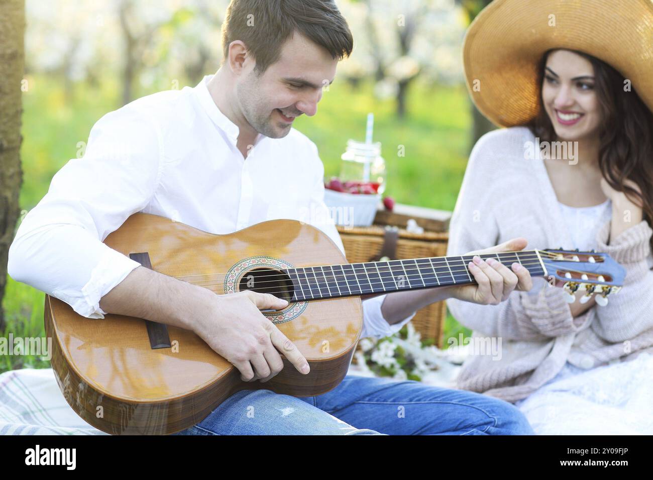 Jeune couple amoureux au pique-nique dans le jardin en fleurs au printemps. Concept de bonheur et d'amour Banque D'Images
