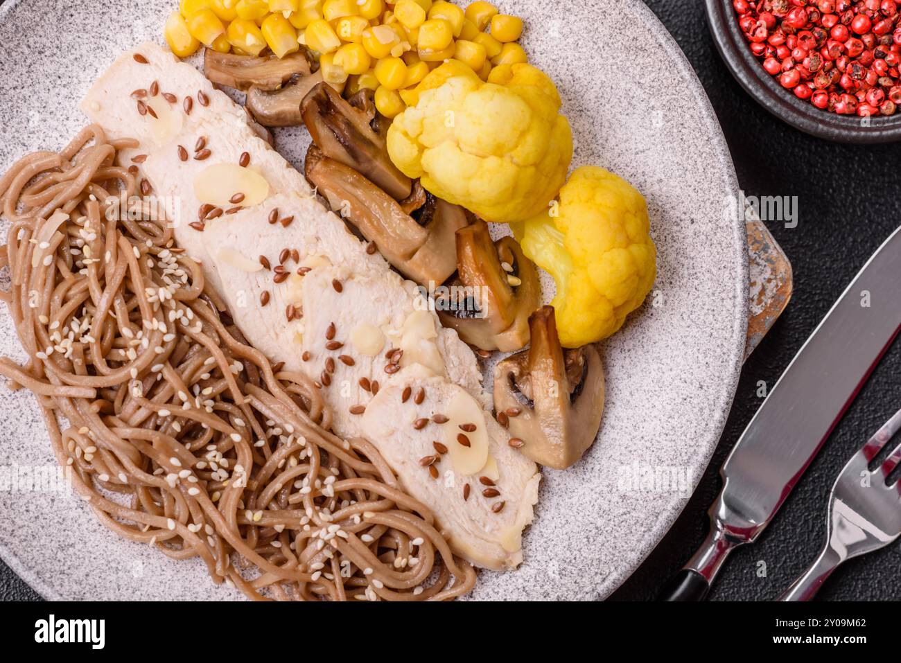 Plat asiatique avec filet de poulet tranché, nouilles de sarrasin, sauce soja, chou-fleur et maïs Banque D'Images