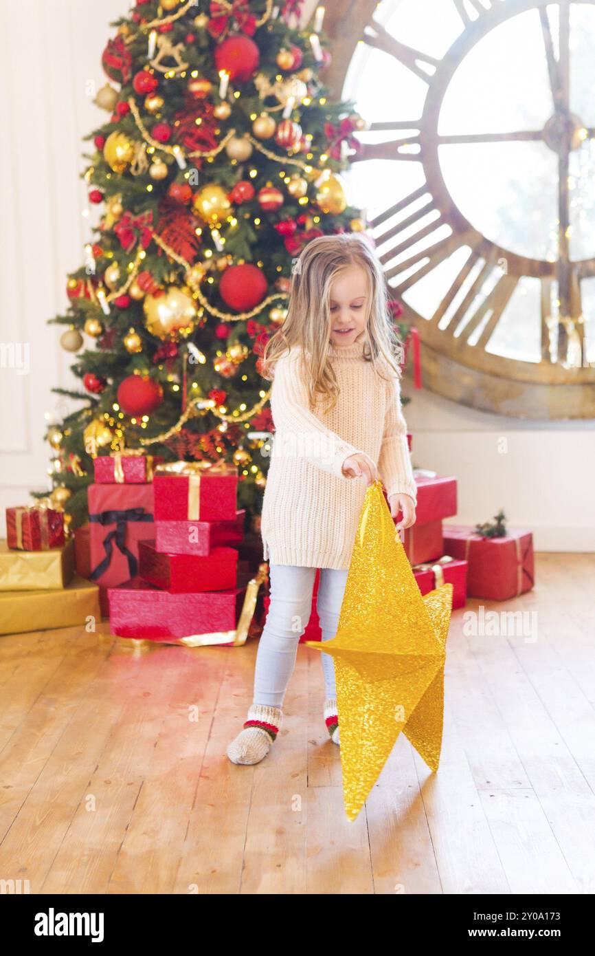 Cute little girl avec l'étoile de Noël avec sapin de Noël sur fond de Banque D'Images