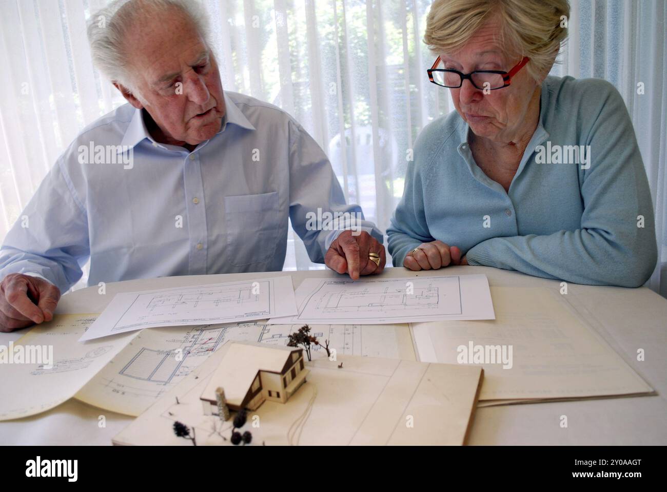 Couple senior regardant un plan de terrain et un modèle de maison Banque D'Images