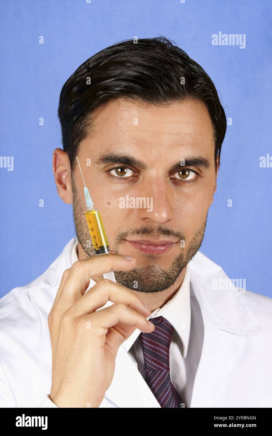 Beau docteur tenant une seringue avec du liquide jaune. Sur un fond bleu clair Banque D'Images