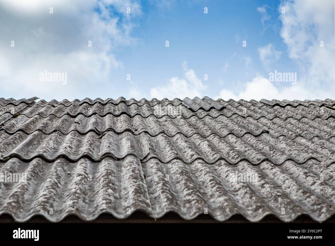 Feuilles d'amiante grises sur un toit de maison, vue panoramique avec ciel bleu Banque D'Images