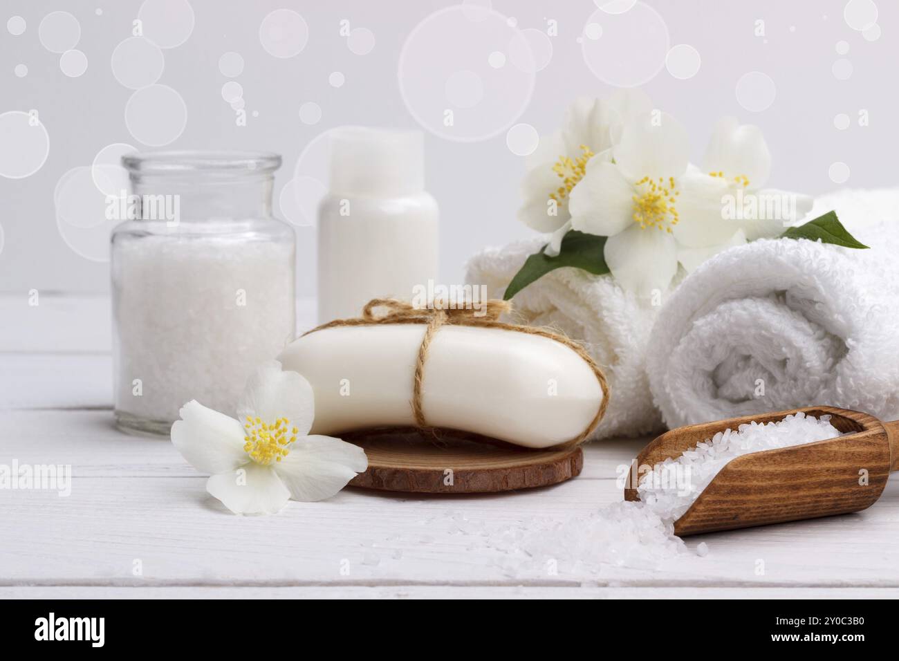 Cadre de spa et articles de soins de santé, savon aromatique de jasmin, huile corporelle, sel de bain, lait, pierres de massage et serviettes, sur planche de bois Banque D'Images