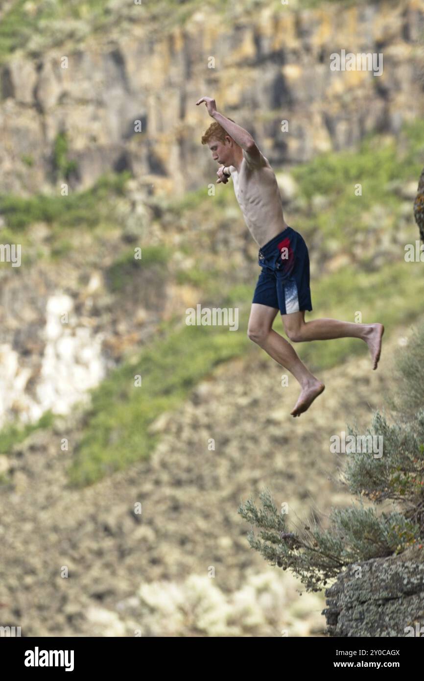 Un jeune homme saute d'une falaise dans l'eau en contrebas à Twin Falls, Idaho Banque D'Images