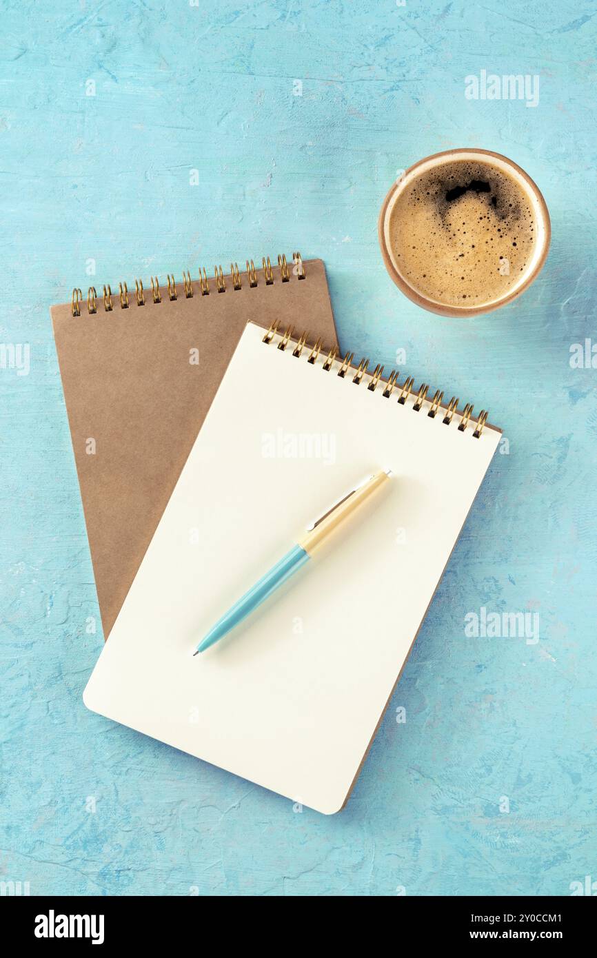 Maquette de cahier avec un stylo et une tasse de café, top shot sur un fond turquoise Banque D'Images