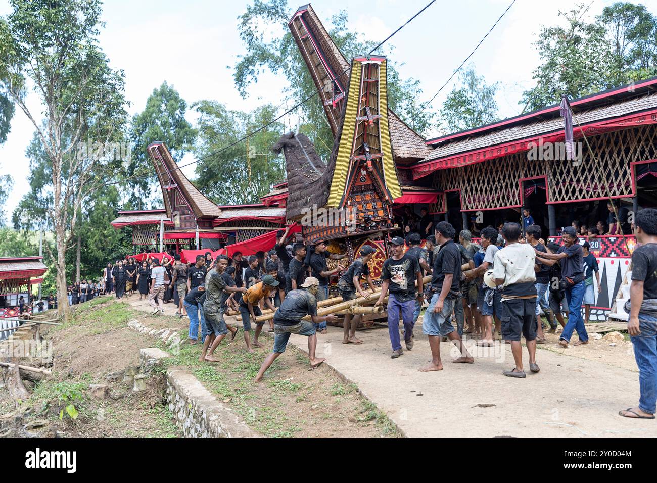 Cérémonie funéraire dans un village près de Rantepao à Tana Toraja, des hommes locaux portant un cercueil, le corbillard en forme de maison traditionnelle, Sulawesi Banque D'Images