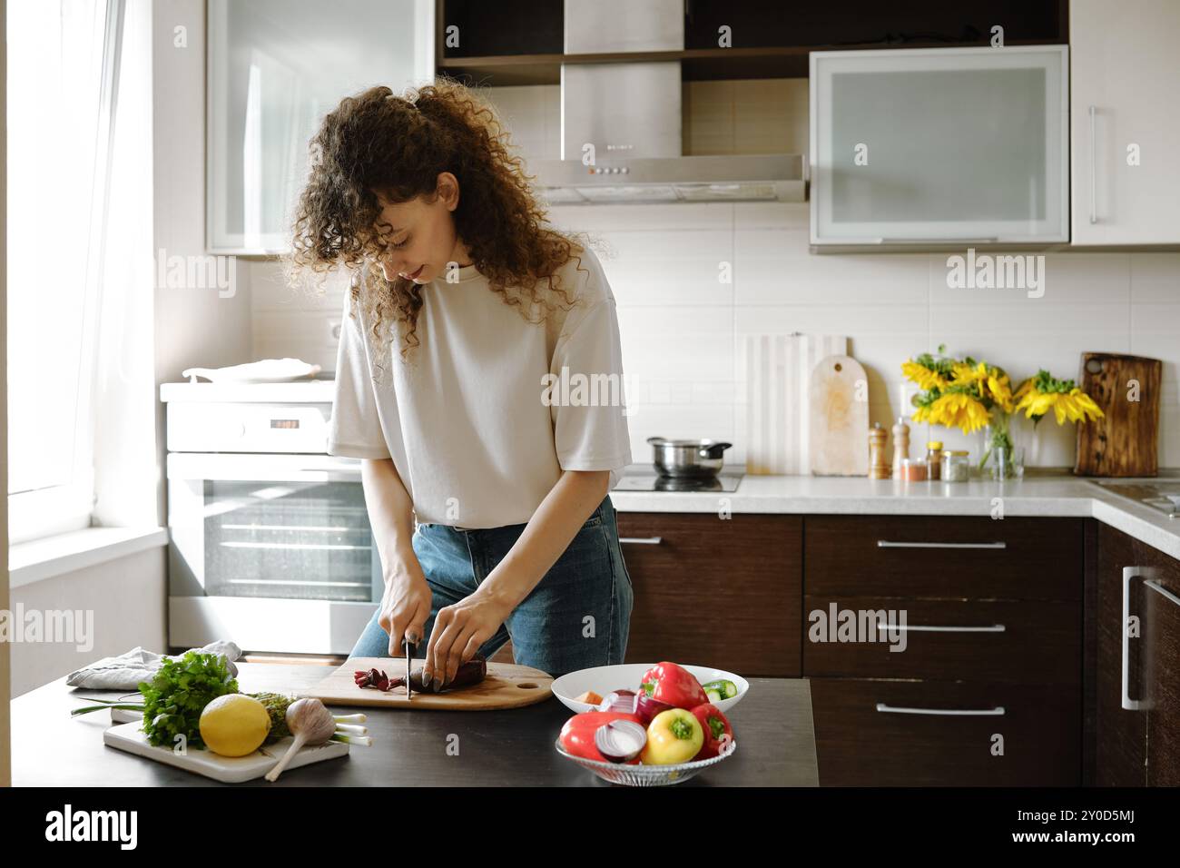 Jeune femme au foyer épluchant la betterave biologique fraîche tout en préparant le repas dans la cuisine Banque D'Images