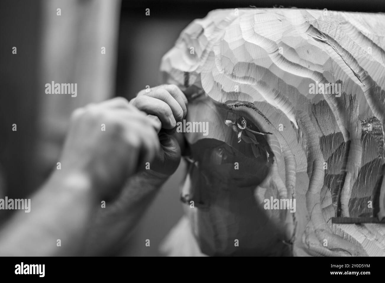 Image captivante de l'artiste sculptant sculpture en bois dans un atelier confortable avec un ciseau. Les détails complexes et la précision mettent en valeur le talent et la créativité. Bla Banque D'Images