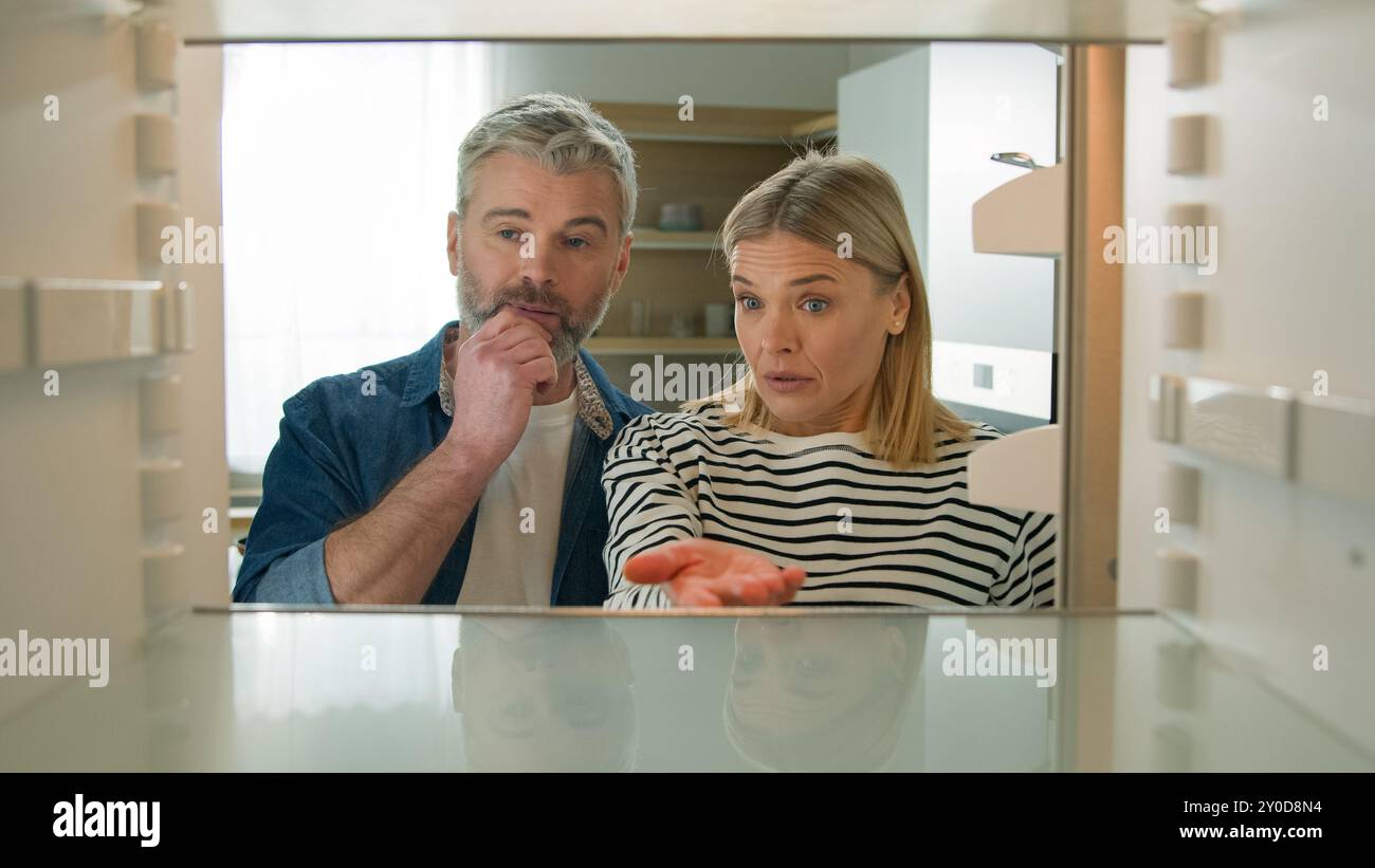 Point de vue POV de l'intérieur réfrigérateur Caucasien famille adulte couple mature homme d'âge moyen femme ouvert vide réfrigérateur n'ont rien à manger triste bouleversement Banque D'Images