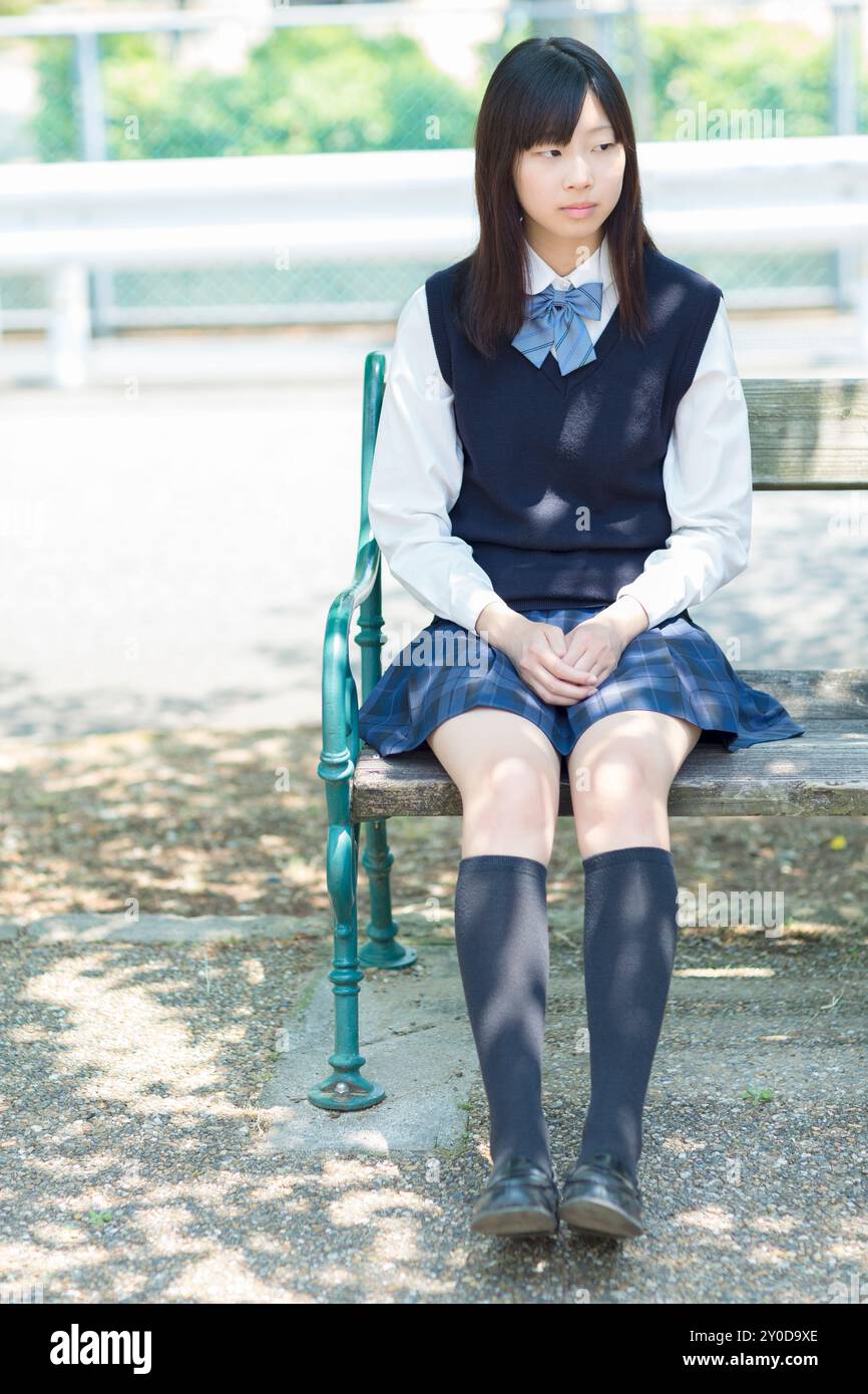 Une écolière japonaise assise sur le banc Banque D'Images