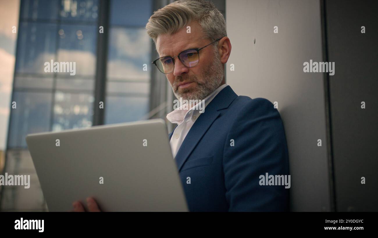 Mature concentré senior d'employeur d'âge moyen entrepreneur occupé commerçant d'homme d'affaires vieil homme d'affaires retraité mis sur des lunettes de travail regardant l'ordinateur portable Banque D'Images