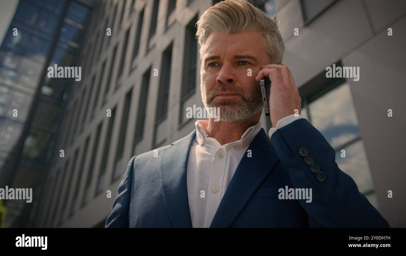 Sérieux irrité confiant entrepreneur émotionnel parler conflit smartphone expliquer discuter de problème de travail parler homme d'affaires senior d'âge moyen Banque D'Images