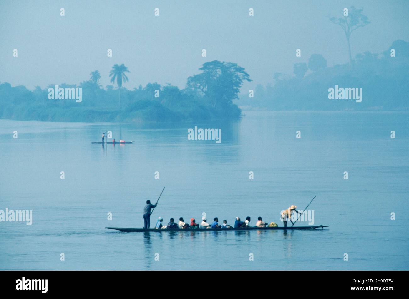 Les passagers sont transportés à travers le fleuve Congo par deux hommes qui utilisent de longues rames pour pagayer sur un canot ou pirogue. Banque D'Images