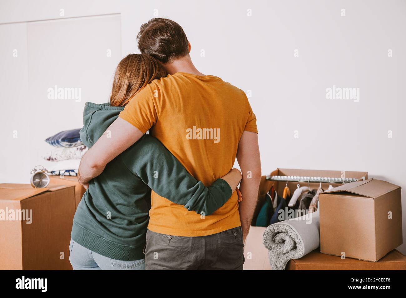 Le couple se tient à proximité, se serrant par derrière tout en regardant les boîtes en mouvement, partageant l'étreinte pendant le déballage Banque D'Images