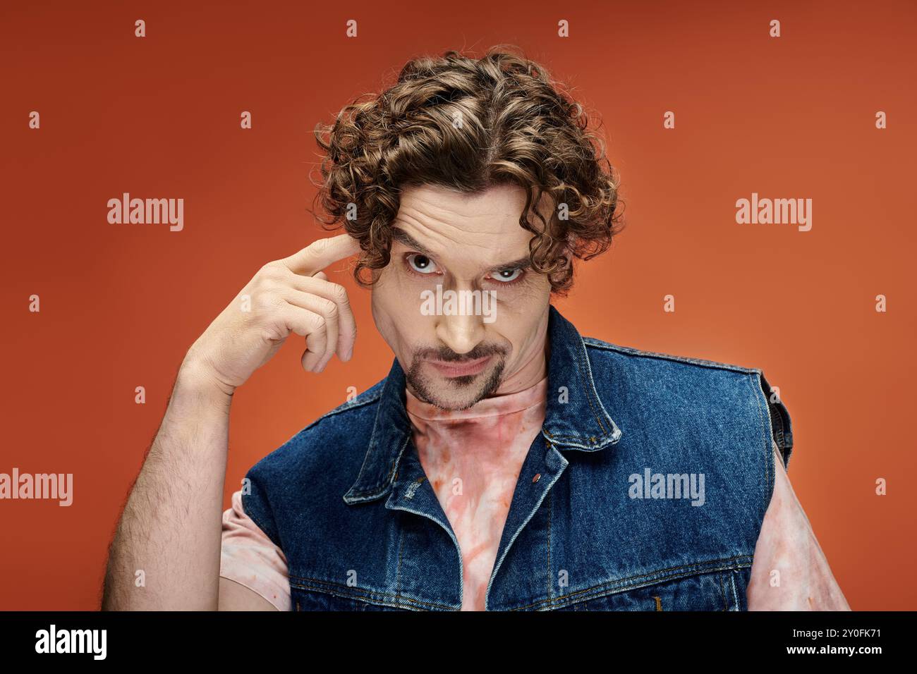 Un homme aux cheveux bouclés transmet une émotion profonde dans un cadre coloré. Banque D'Images