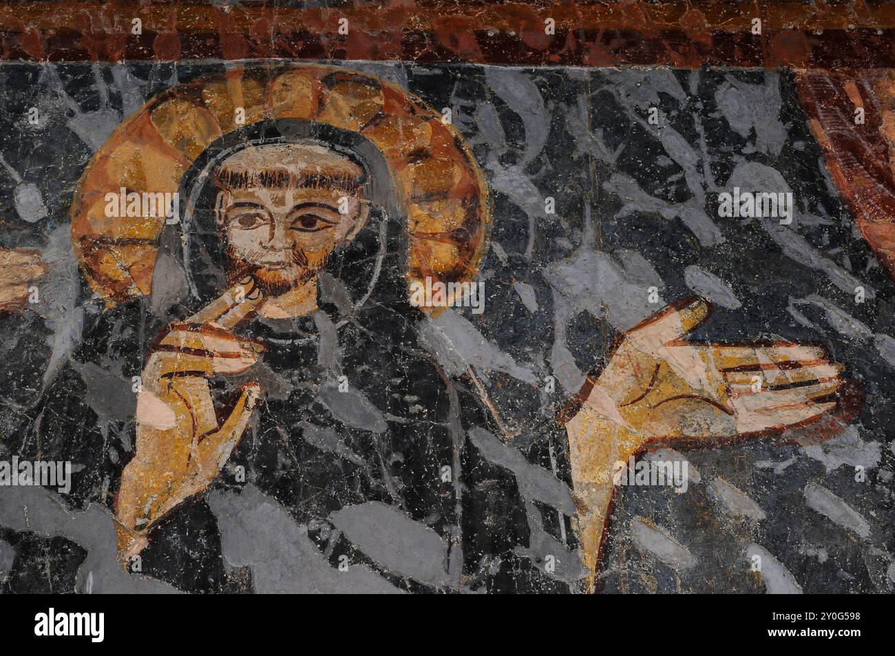 Moine Saint tonsured avec d'énormes mains en détail d'une tentation endommagée de la fresque de Saint Benoît, peinte à la fin des années 1200, dans le cloître de l'Abbazia di Piona (Abbaye de Piona), Colico, Lombardie, Italie. Banque D'Images