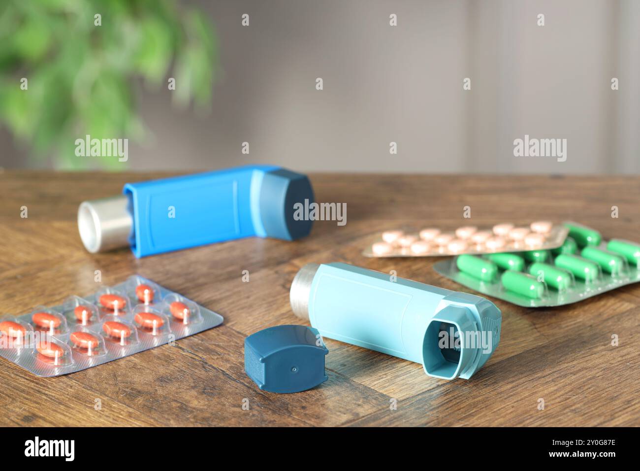 Inhalateurs et pilules sur la table en bois à l'intérieur, gros plan. Traitement de l'asthme Banque D'Images