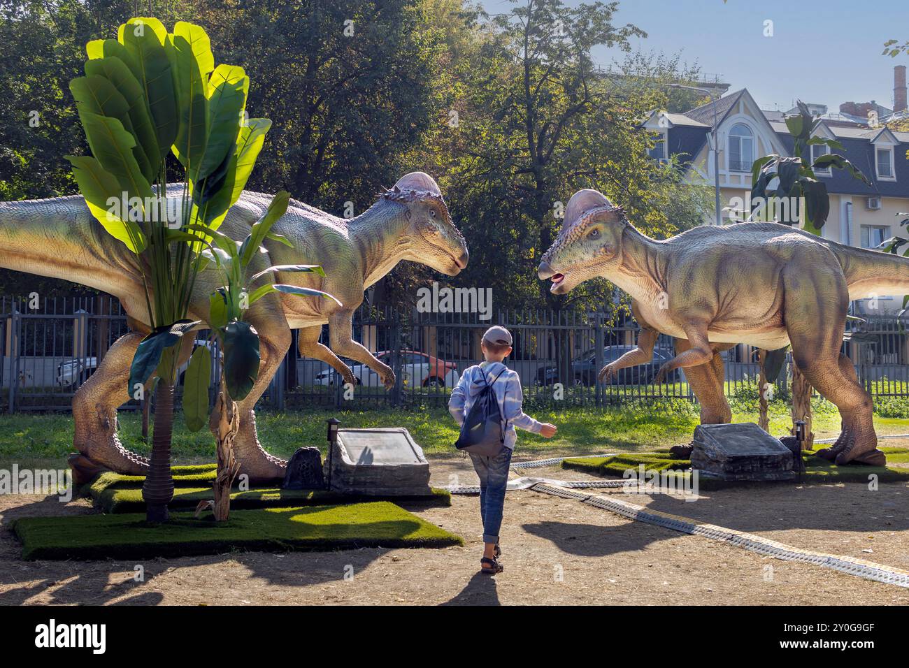 Garçon entre deux dinosaures de taille réelle dans un parc d'attractions. Banque D'Images