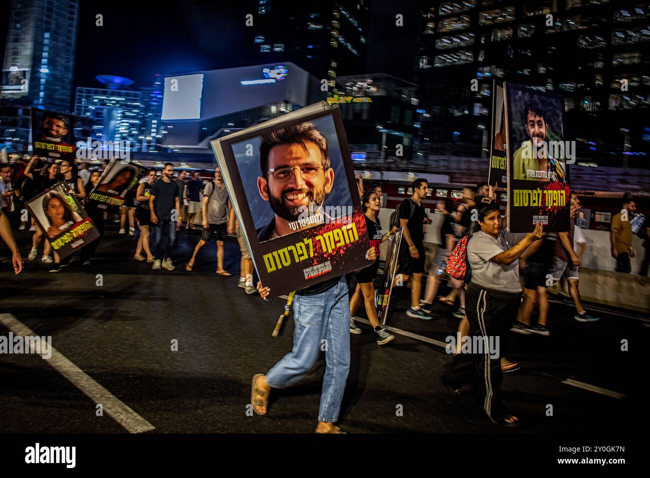 Les manifestants défilent avec des pancartes avec des portraits d'Almog Sarusi, (l), et Hersh Goldberg Polin pendant la manifestation. Les organisateurs affirment que plus de 700 000 Israéliens sont descendus dans les rues des villes du pays dimanche soir après que les corps de Carmel Gat, Eden Yerushalmi, Hersh Goldberg-Polin, Alexander Lobanov, Almog Sarusi et Maître Sgt Ori Danino, aient été sauvés de Gaza. Les manifestants ont exigé que le premier ministre Benjamin Netanyahu conclue un accord de cessez-le-feu avec le Hamas pour ramener les prisonniers restants chez eux. Banque D'Images