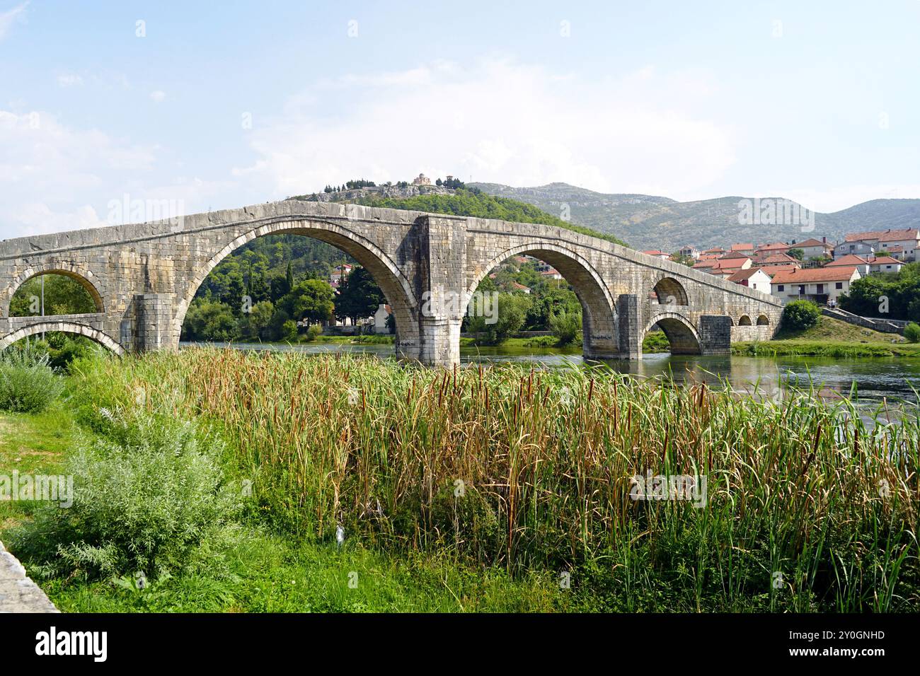 Paysage d'été avec pont Arslanagic à Trebinje, Bosnie-Herzégovine. Rivière avec des queues, pont de pierre avec de grandes arches et des montagnes Banque D'Images
