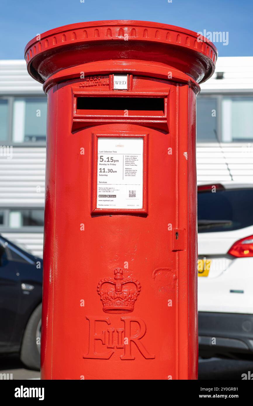 Vue de face rapprochée d'une boîte aux lettres Royal mail extérieure devant des voitures stationnées et un immeuble de bureaux. Banque D'Images