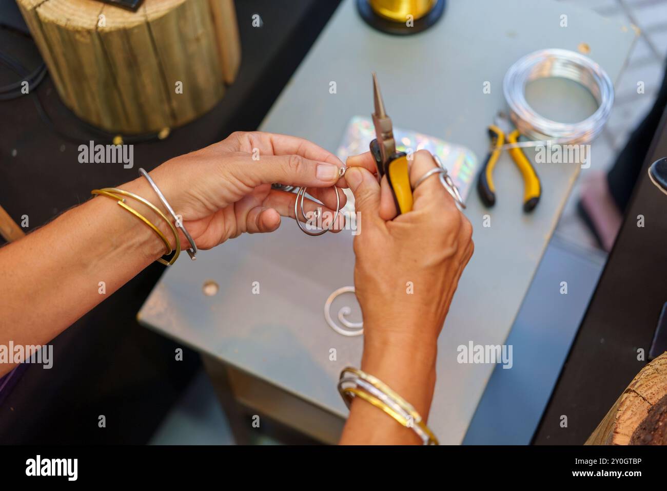 Femme hispanique méconnaissable dans ses années 50 Crafting boucles d'oreilles à son stand de rue vendant des bijoux en fil d'aluminium faits à la main Banque D'Images