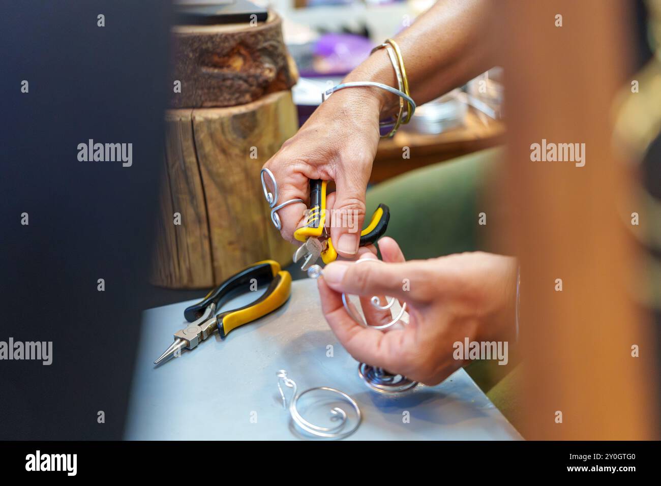 Femme hispanique méconnaissable dans ses années 50 Crafting boucles d'oreilles à son stand de rue vendant des bijoux en fil d'aluminium faits à la main Banque D'Images