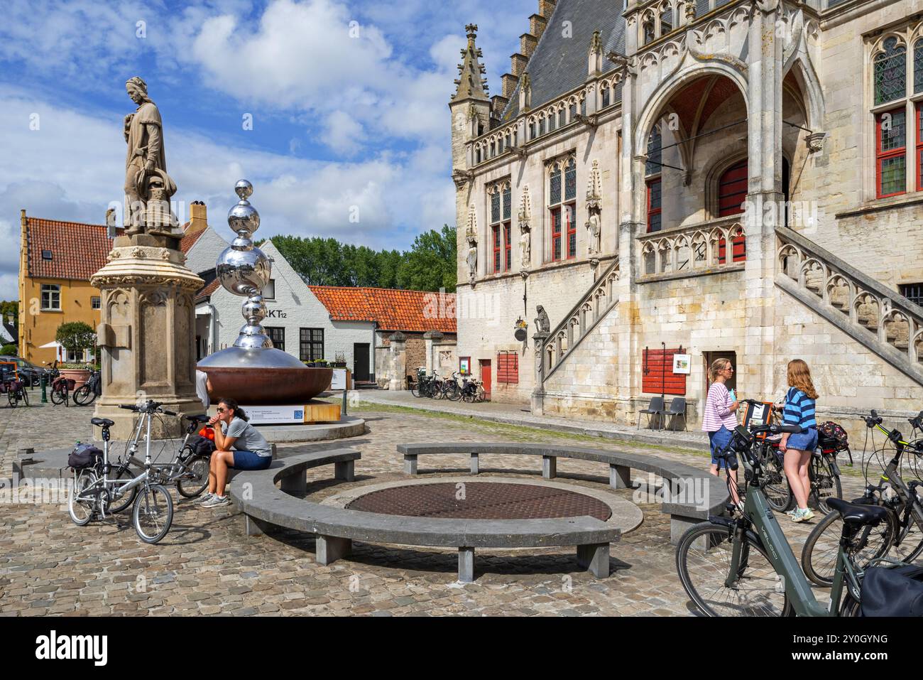 Statue de Jacob van Maerlant et des cyclistes devant la mairie gothique brabantine dans la ville de Damme en été, Flandre occidentale, Belgique Banque D'Images