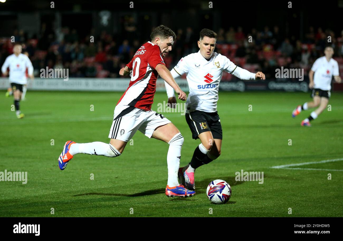 Dan Chesters de Salford City tente un cross face à Liam Kelly de Milton Keynes dons lors du match de Sky Bet League Two au Peninsula Stadium de Salford. Date de la photo : lundi 2 septembre 2024. Banque D'Images