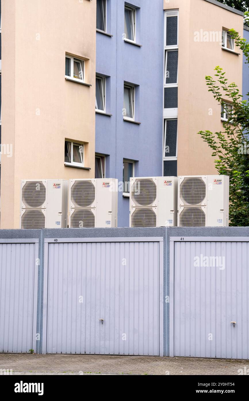 Pompes à chaleur dans une zone résidentielle, les maisons multifamiliales sont alimentées en chauffage, en refroidissement et en eau chaude sanitaire via ces appareils, montés sur le garage R. Banque D'Images