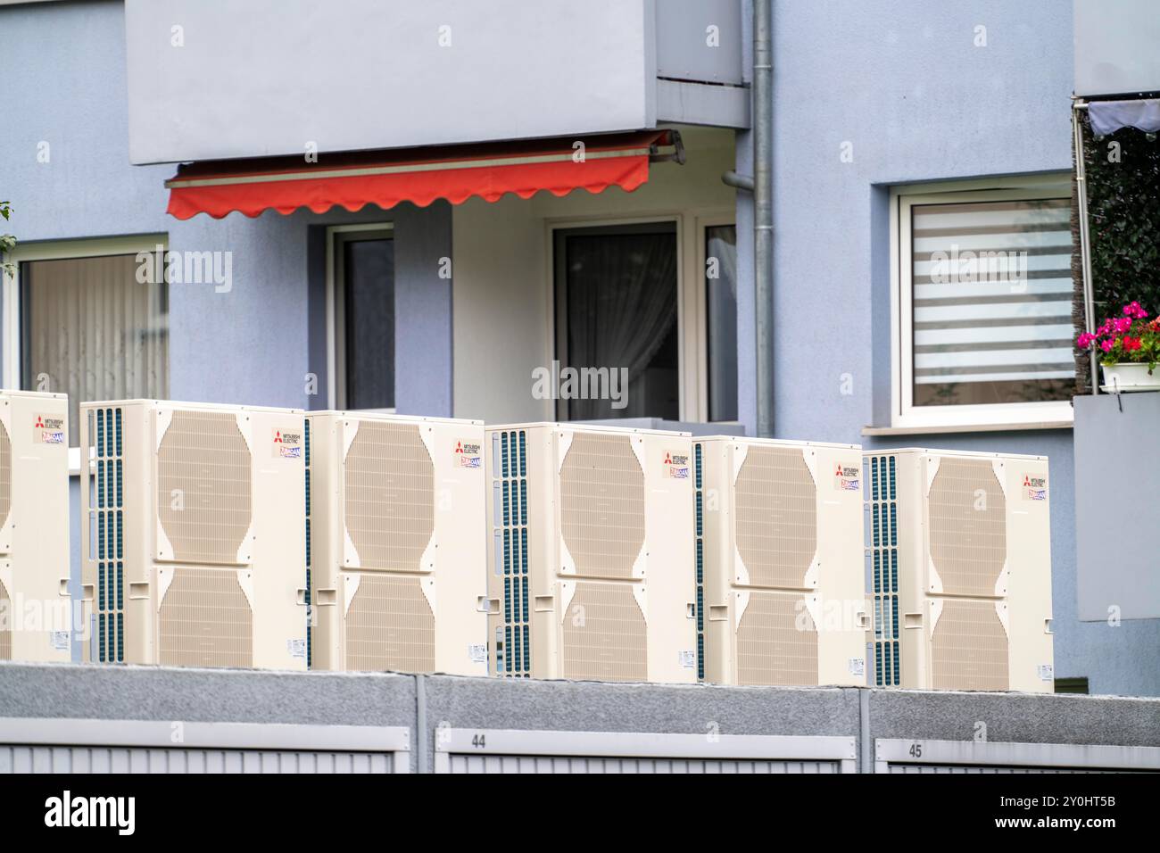 Pompes à chaleur dans une zone résidentielle, les maisons multifamiliales sont alimentées en chauffage, en refroidissement et en eau chaude sanitaire via ces appareils, montés sur le garage R. Banque D'Images