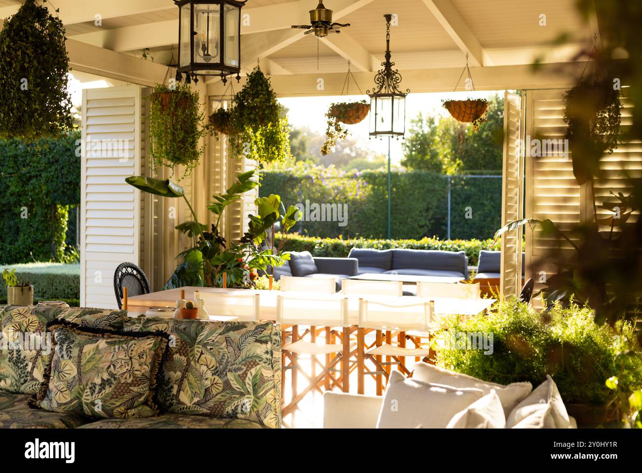 Patio ensoleillé avec plantes luxuriantes et sièges confortables pour la détente en famille Banque D'Images