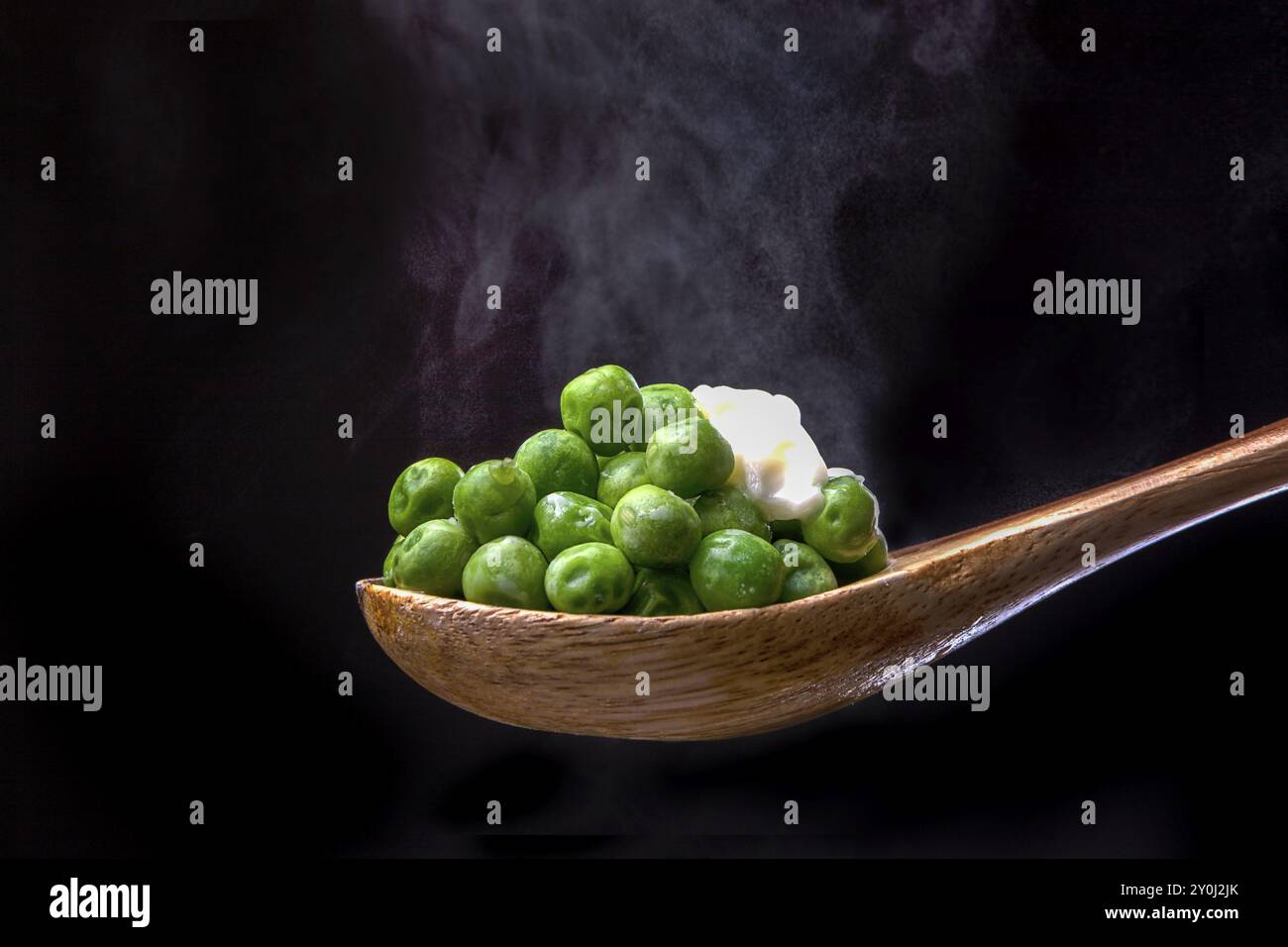 Pois garni de beurre sur une cuillère en bois avec de la vapeur par en-dessous Banque D'Images