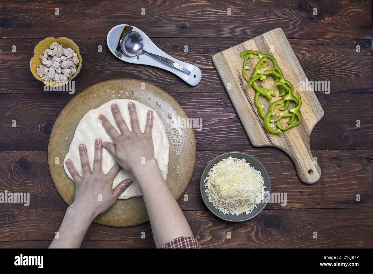 Une vue sur les mains étalant la pâte à pizza sur un plat à pizza Banque D'Images