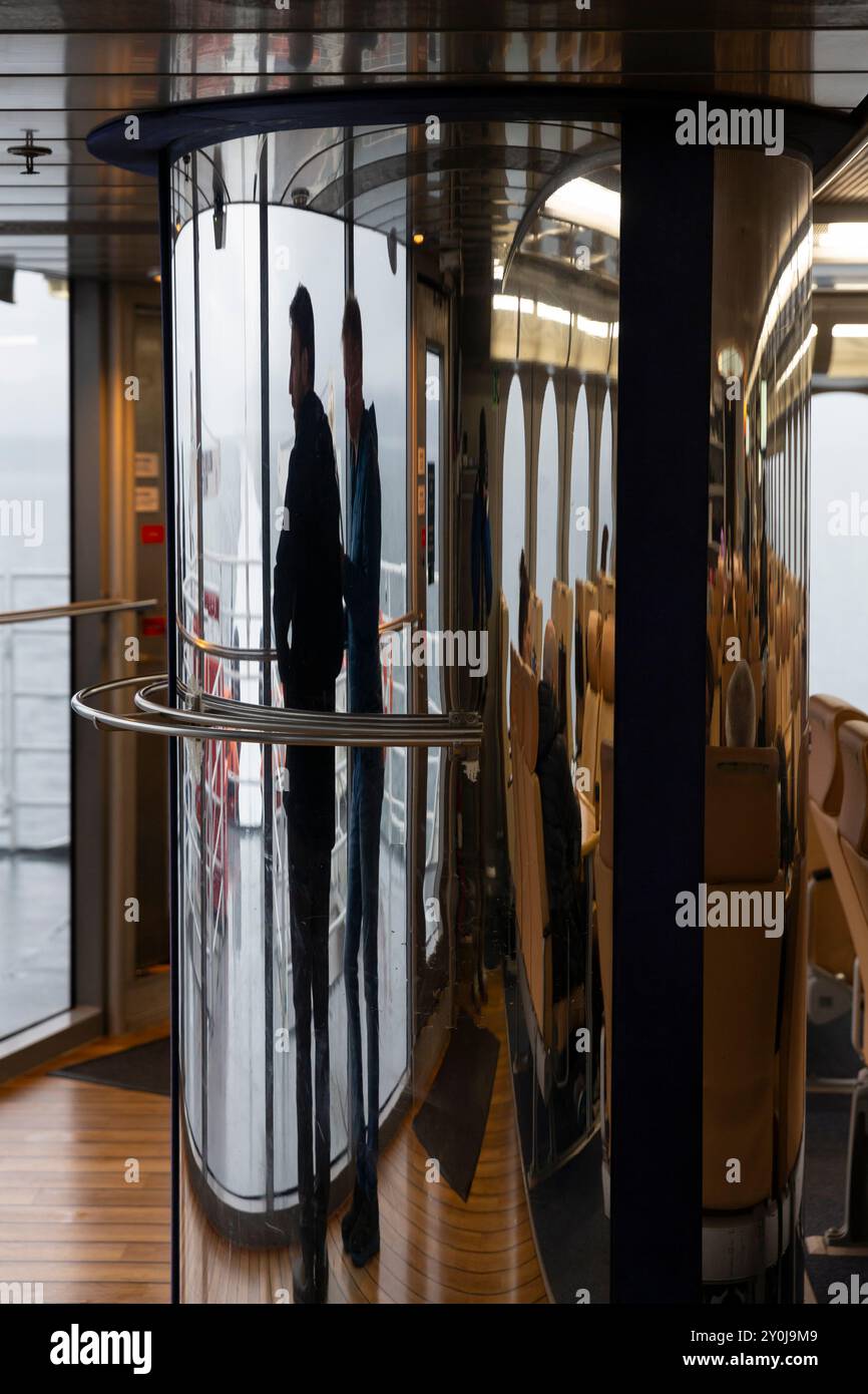 L'image d'un jeune couple regardant vers la mer des Salish est déformée dans un miroir courbé alors qu'il emprunte le traversier Victoria Clipper V pour Victoria, en Colombie-Britannique Banque D'Images