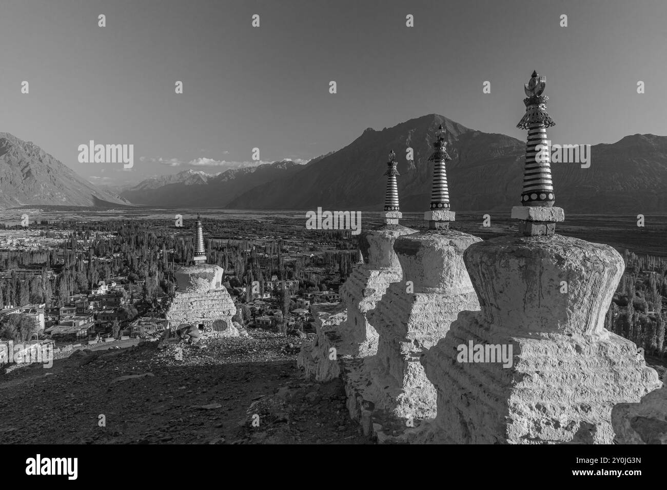 Beaucoup de stupas blancs dans une rangée avec des chaînes de montagnes en arrière-plan. Banque D'Images