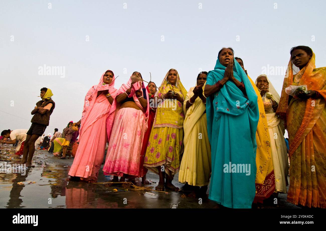 Des femmes indiennes exécutent un puja près de l'eau sainte du Ganga à Gangasagar, au Bengale occidental, en Inde. Banque D'Images