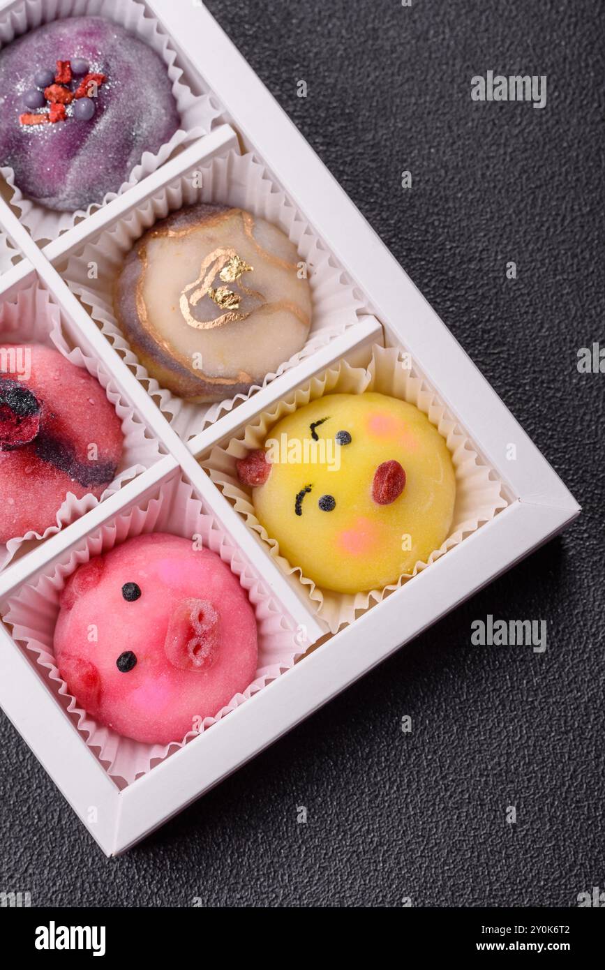 Délicieux dessert mochi japonais froid avec coquille de pâte de riz colorée et remplissage de fruits sur fond de béton foncé Banque D'Images