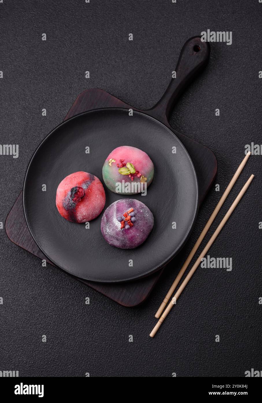 Délicieux dessert mochi japonais froid avec coquille de pâte de riz colorée et remplissage de fruits sur fond de béton foncé Banque D'Images