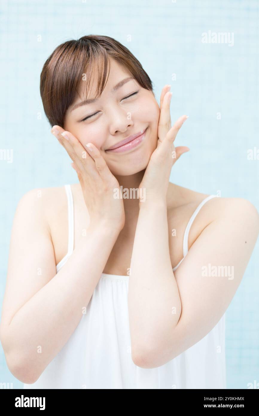 Femme souriante mettant les mains à la joue, image de soin de la peau Banque D'Images Femme souriante mettant les mains à la joue, image de soin de la peau Banque D'Images