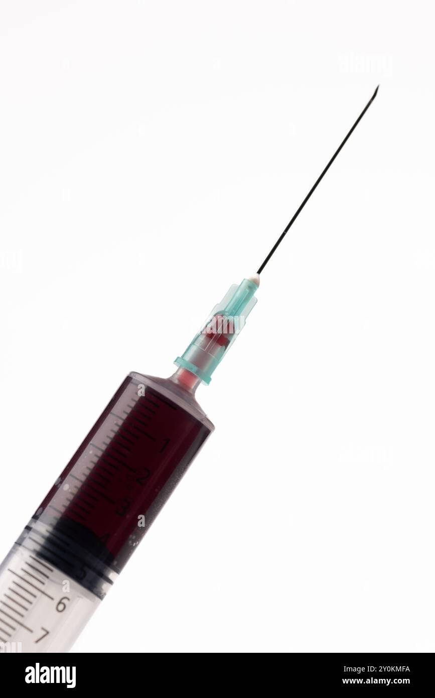 L'aiguille d'une seringue, remplie de sang, bien visible au centre de la photo verticale Banque D'Images
