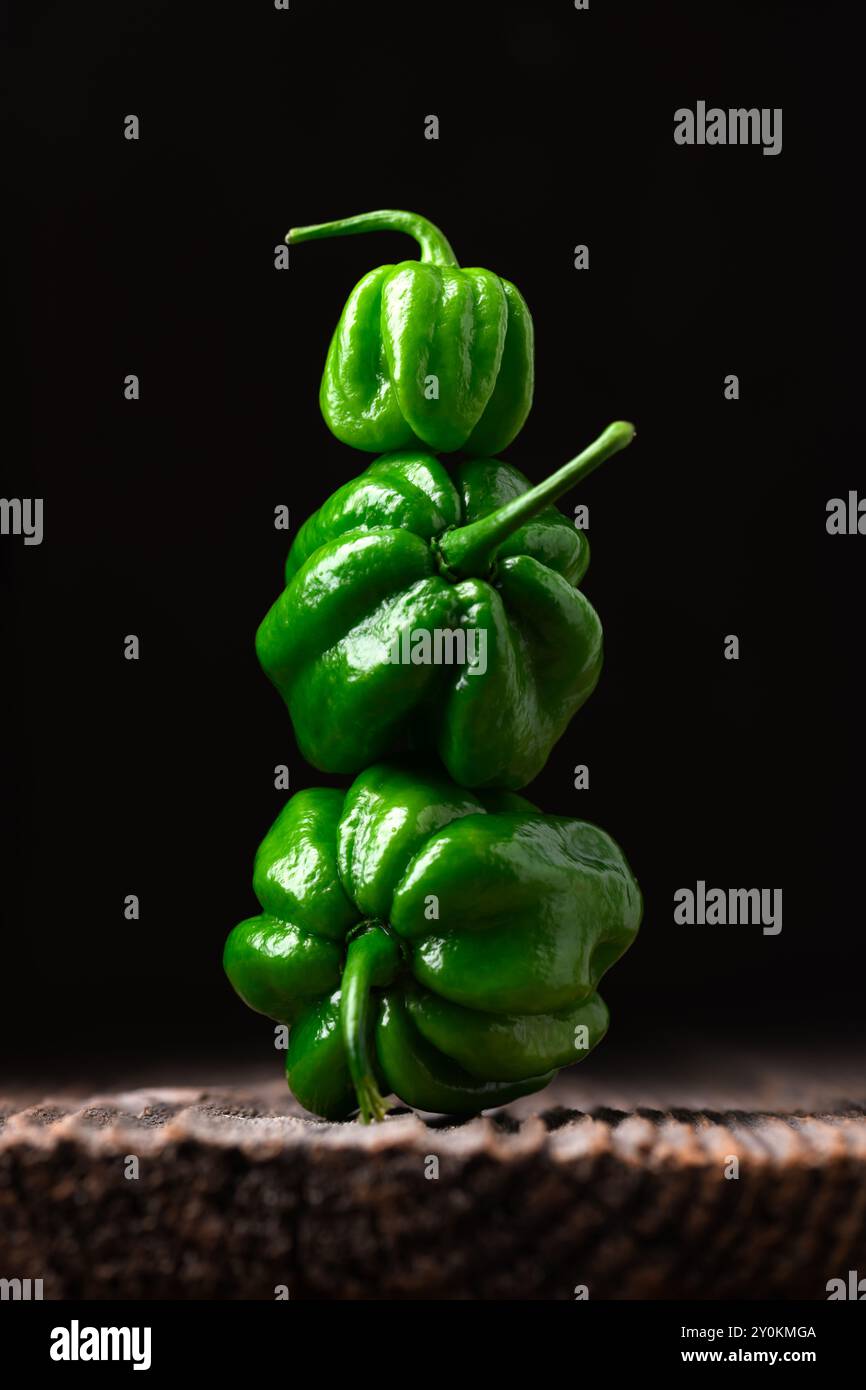 Tour de poivrons habanero verts mûrs (capsicum chinense) sur fond noir. Poivrons mexicains très chauds sur la table en bois rustique de près Banque D'Images