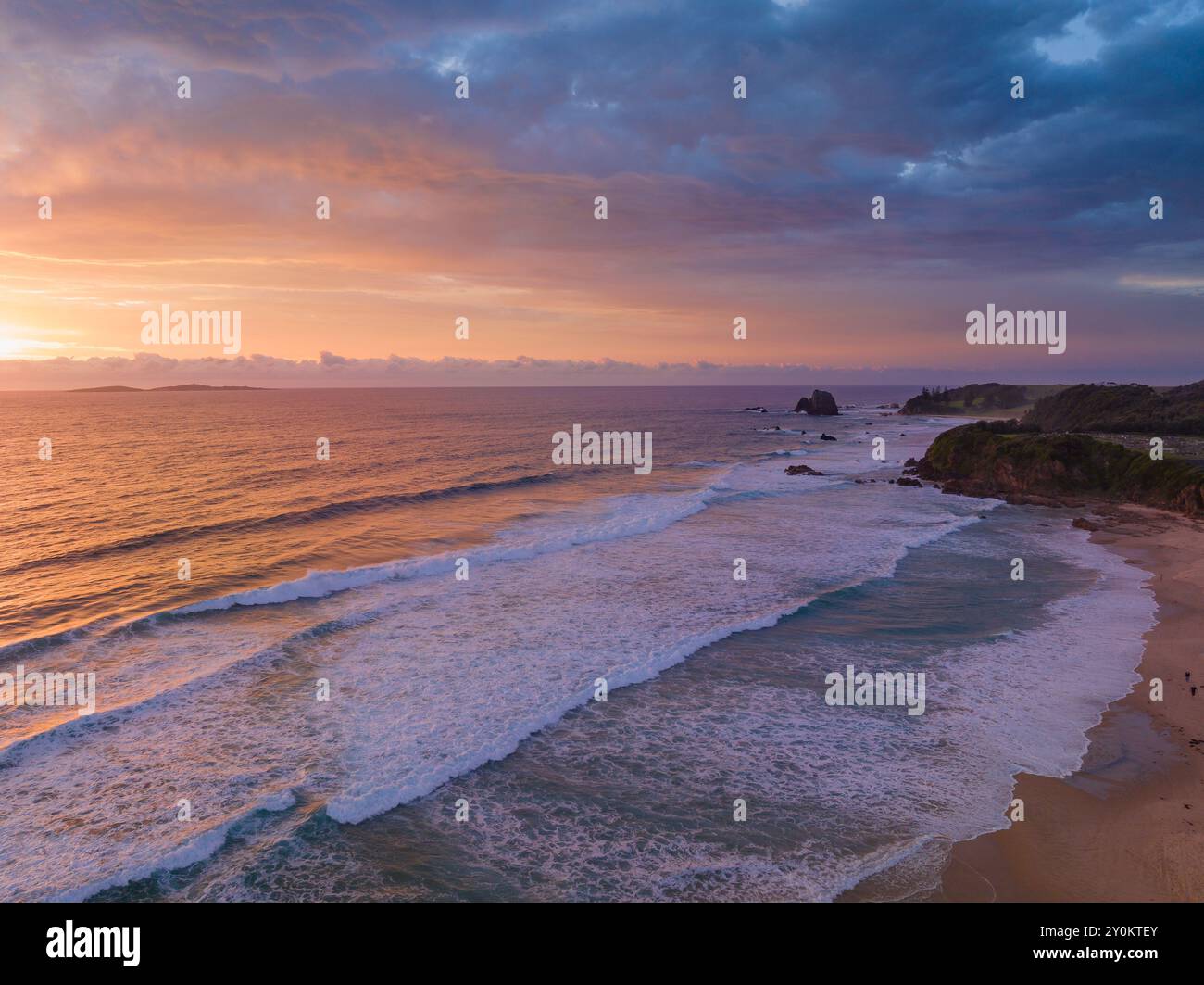 Vue aéariale d'un lever de soleil coloré sur les vagues s'écrasant sur une plage de Narooma sur la côte sud de la Nouvelle-Galles du Sud Banque D'Images