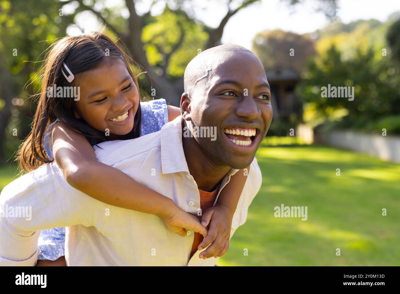 Père donnant à sa fille un tour de piggyback, à la fois souriant et profitant du temps en plein air Banque D'Images