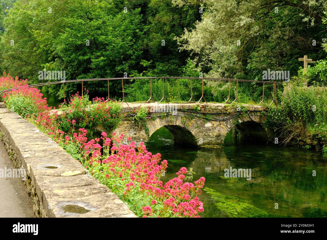 Pont de pierre sur la rivière Coln aux chalets Arlington Row dans le village Cotswold de Bibury, Angleterre, Royaume-Uni Banque D'Images