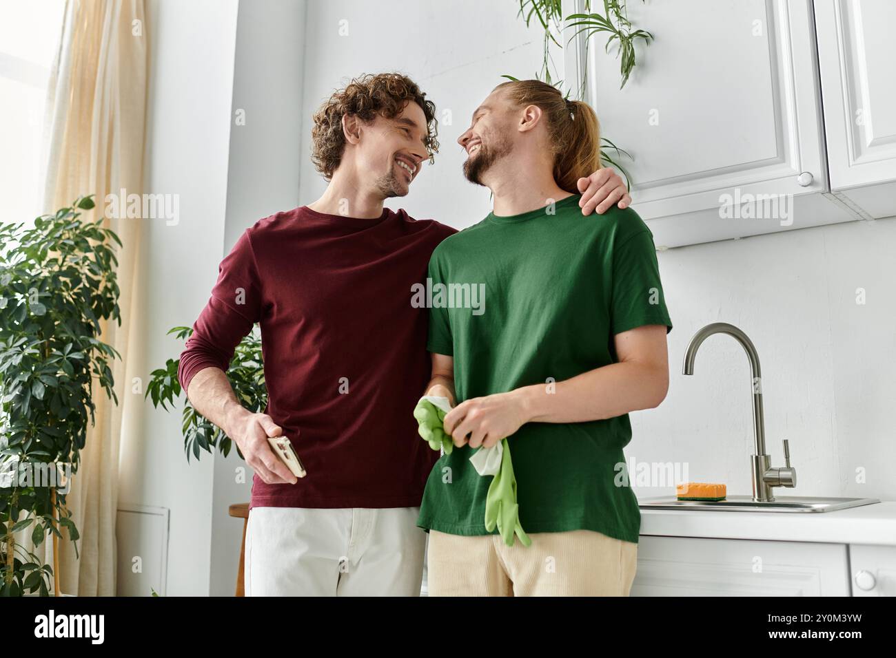 Un couple aimant profite d'un moment tendre tout en rangeant leur cuisine lumineuse. Banque D'Images