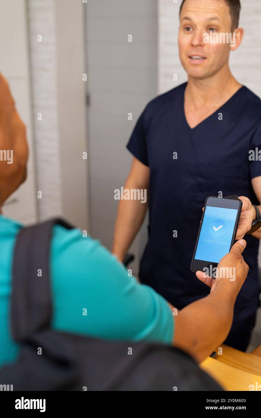 Payer avec smartphone, médecin masculin ou travailleur de la santé dans les gommages, patient visitant la clinique médicale Banque D'Images