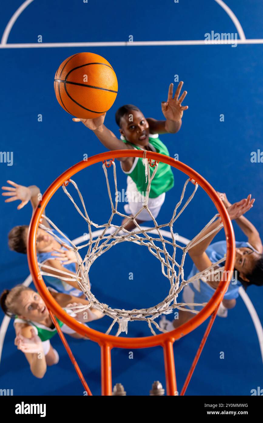 Jouer au basket-ball, fille en maillot vert sautant pour marquer le panier Banque D'Images
